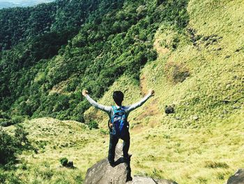 Rear view of man on mountain with arms outstretched