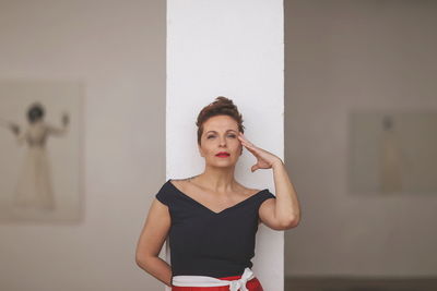 Portrait of mid adult woman standing against column