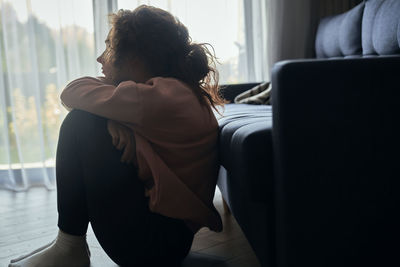 Rear view of woman sitting on sofa at home