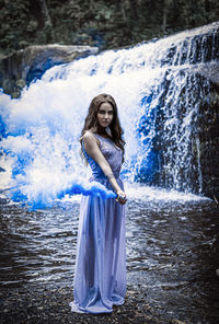 Portrait of woman standing against waterfall