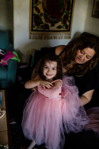 Aunt helping niece put on dress