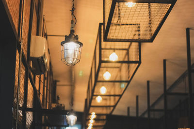 Low angle view of illuminated lighting equipment hanging from ceiling