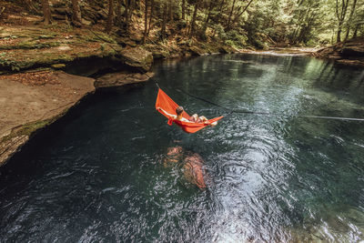 Man rests in hammock over beautiful, blue spring in upstate new york,