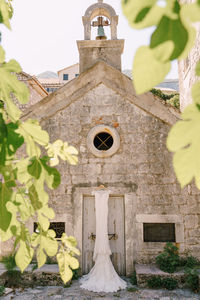 Low angle view of cross by building against sky