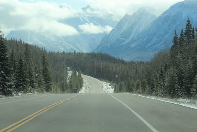 Road amidst trees and mountains against sky