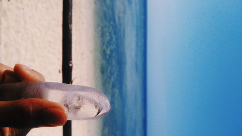 Close-up of hand holding ice at beach