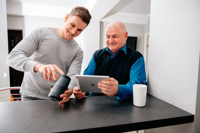 Man using digital tablet by grandfather at home