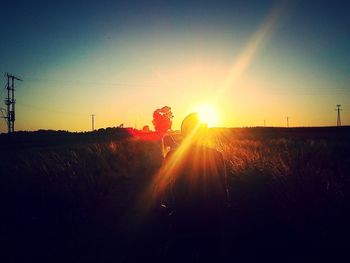 People standing on field at sunset