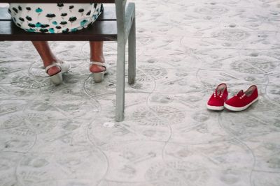 Low section of person wearing shoes on sand