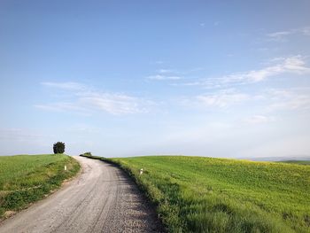 Road amidst field against sky