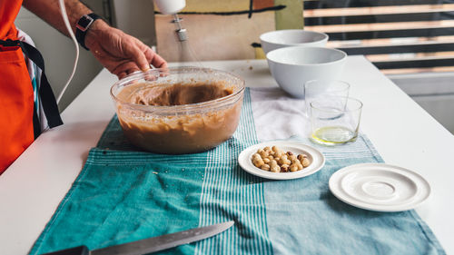 Cropped image of man preparing batter in bowl at table in kitchen