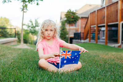 Cute girl with flag sitting on field