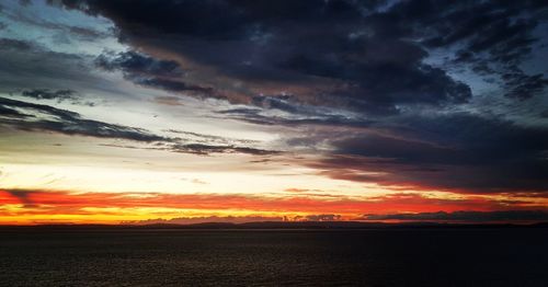 Scenic view of sea against dramatic sky during sunset