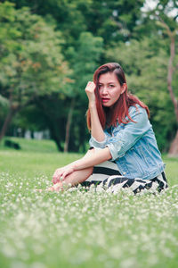 Portrait of beautiful young woman sitting on land