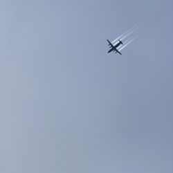 Low angle view of airplane flying against clear blue sky