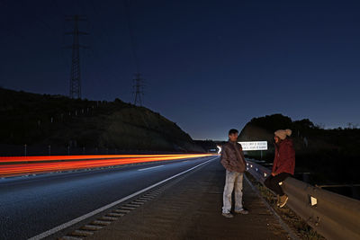 People standing on road against blue sky