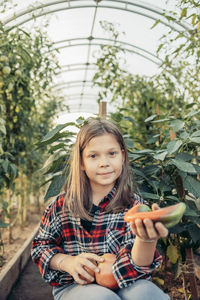 Portrait of young woman standing against trees