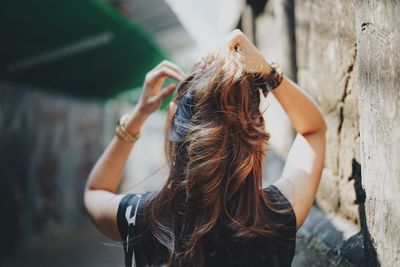 Rear view of woman with arms raised standing outdoors