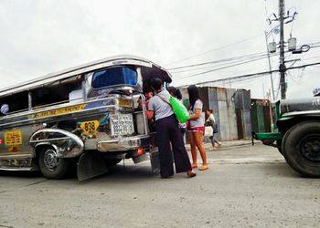 People on road in city against sky