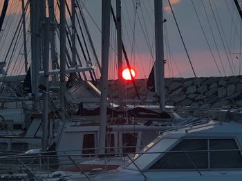 Sailboats in sea against buildings at sunset