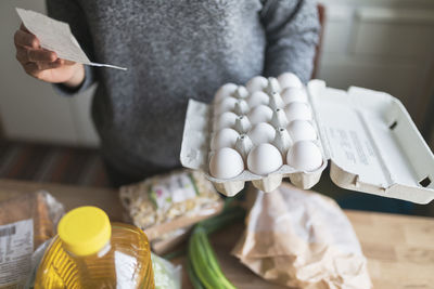 Woman checking receipt from supermarket during inflation with rise in price of food and consumer products