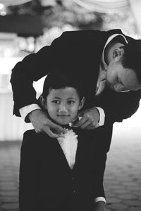 Man adjusting bow tie of son