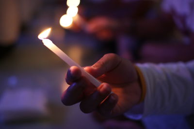 Close-up of hand holding lit candles