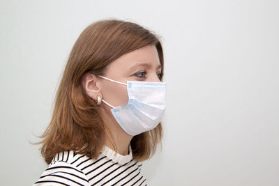 Young woman with protective face mask against white back ground