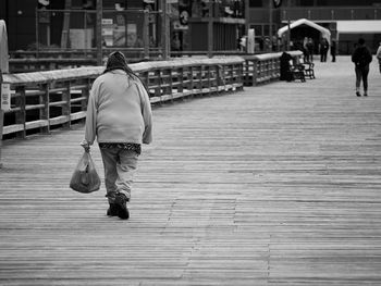 Rear view of woman walking on footpath in city