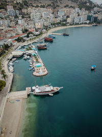 High angle view of sailboats moored on sea by buildings in city