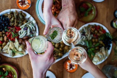 Cropped image of friends toasting drinks over food on table
