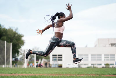 Low angle view of woman jumping against the sky