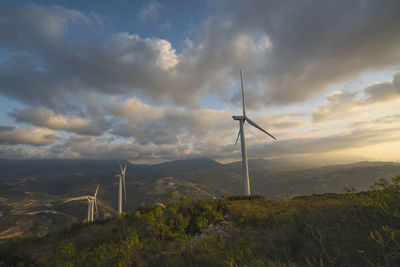 Windmill on field against sky during sunset