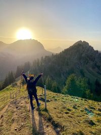 Man standing on mountain road against sky during sunset