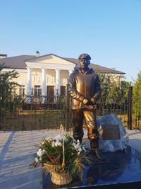 Statue of man standing by building against clear sky