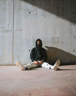 Young man sitting on wall