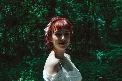 Portrait of young woman against plants