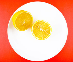 Close-up of lemon slice on table against orange background