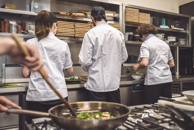 Rear view of chefs working on kitchen counter in restaurant