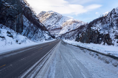 Road amidst snowcapped mountains against sky