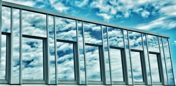 Low angle view of modern building against cloudy sky