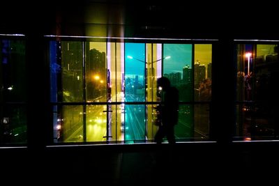 Reflection of silhouette people on glass window at night