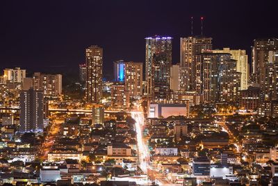 Illuminated cityscape against clear sky at night