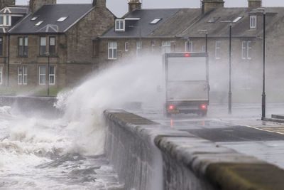 Water splashing on street against buildings in city