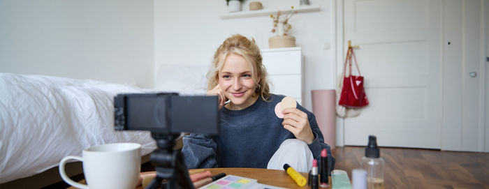 Portrait of young woman using mobile phone while sitting at home