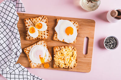 Scrambled egg, poached egg, fried egg, boiled egg on toast on a board top view