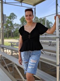 Portrait of young woman standing against railing