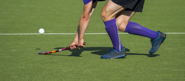Low section of man playing hockey on turf