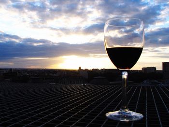 Wineglass against sky during sunset