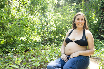 Seven month pregnant woman in a park dressed in jeans